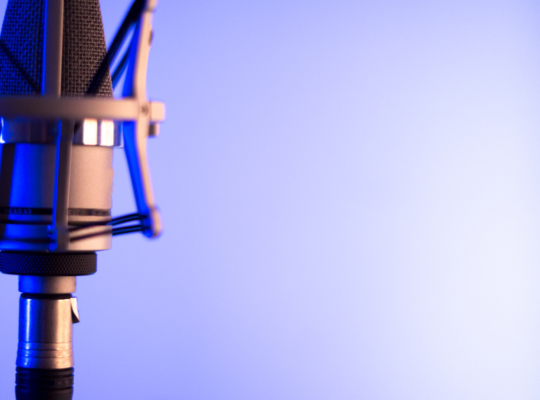 Close up of a microphone against a light vibrant blue background