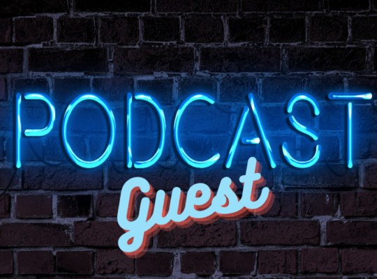 Brick wall with a neon blue sign reading “Podcast Guest”